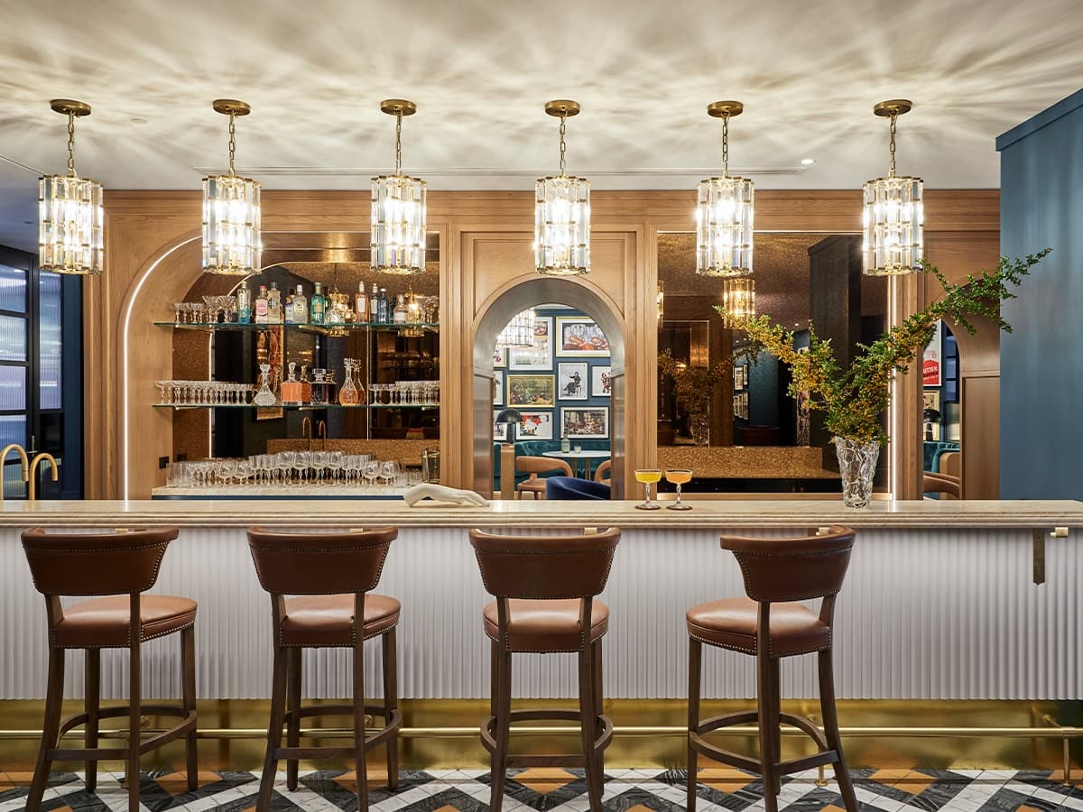 The Bureau Sydney workspace features a luxurious bar with leather stools, ornate lighting, and wood panelling.