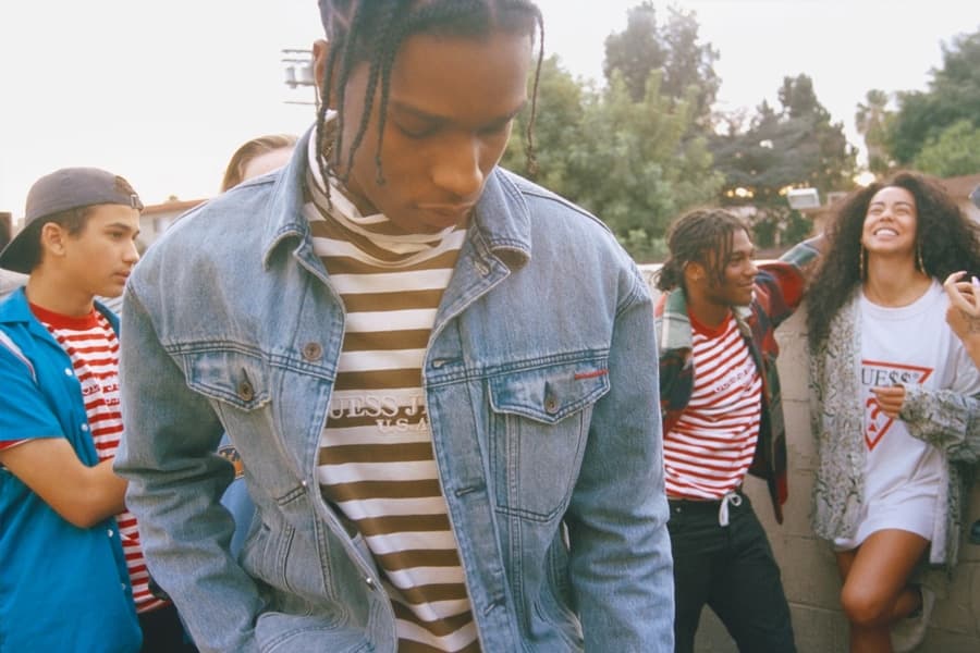 Group of young adults in casual streetwear, including denim jackets and striped shirts, socialising outdoors.