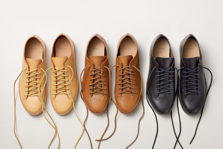 Four pairs of Feit sneakers in tan, brown, and dark grey leather neatly arranged on a light background.