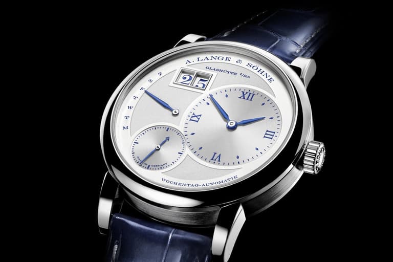 A. Lange & Söhne Lange 1 Daymatic watch with silver dial, blue Roman numerals, and blue leather strap.