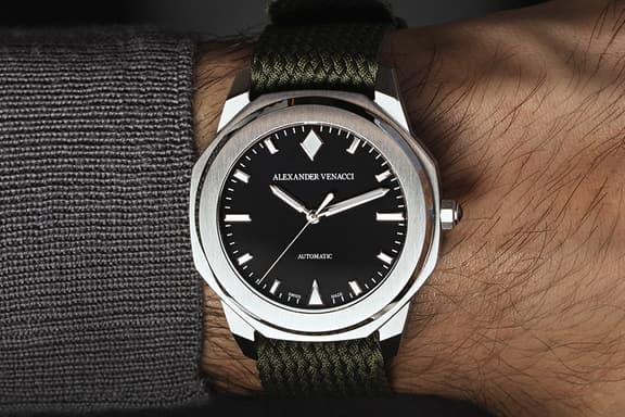 Alexander Venacci watch with black dial and silver bezel on wrist, featuring a green woven strap.