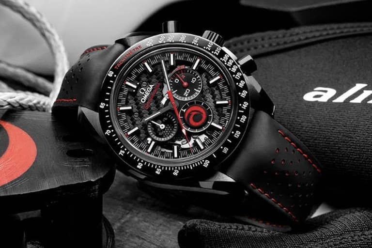 Omega Speedmaster Dark Side of the Moon 'Alinghi' watch with black and red details on a textured surface.