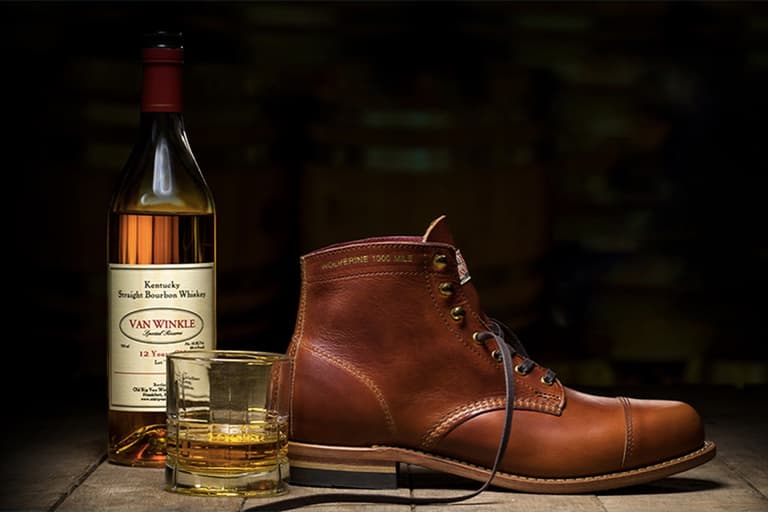 Wolverine Old Rip X 1,000 Mile Boot in brown leather next to Van Winkle whisky bottle and glass on wooden surface.