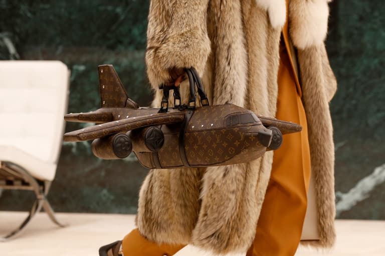 Louis Vuitton Aeroplane Bag in brown monogram carried by person in fur coat and orange trousers.