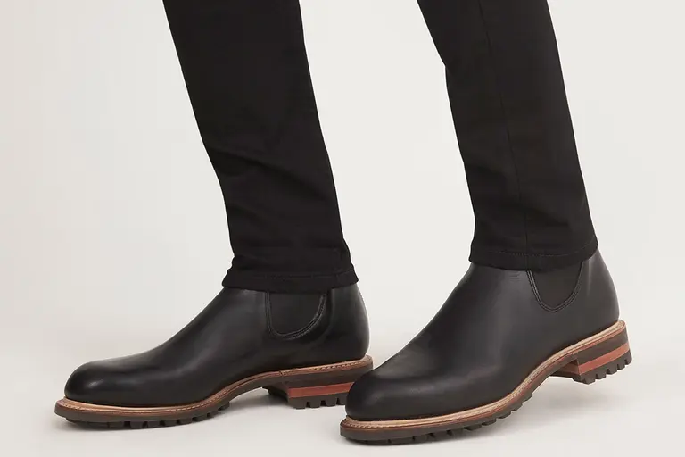 R.M. Williams Gardener Commando Boots in black leather worn with black trousers on a white background.
