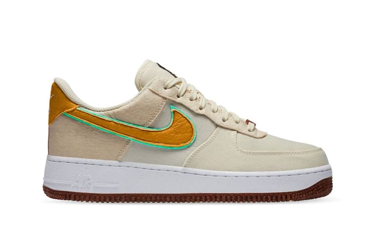 Nike Air Force 1 sneaker in beige with pineapple-themed accents, featuring a yellow swoosh and textured sole.
