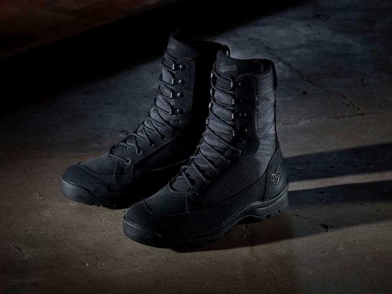 Danner 007 Tanicus Tactical Boots in black on a concrete floor, dimly lit with dramatic shadows.