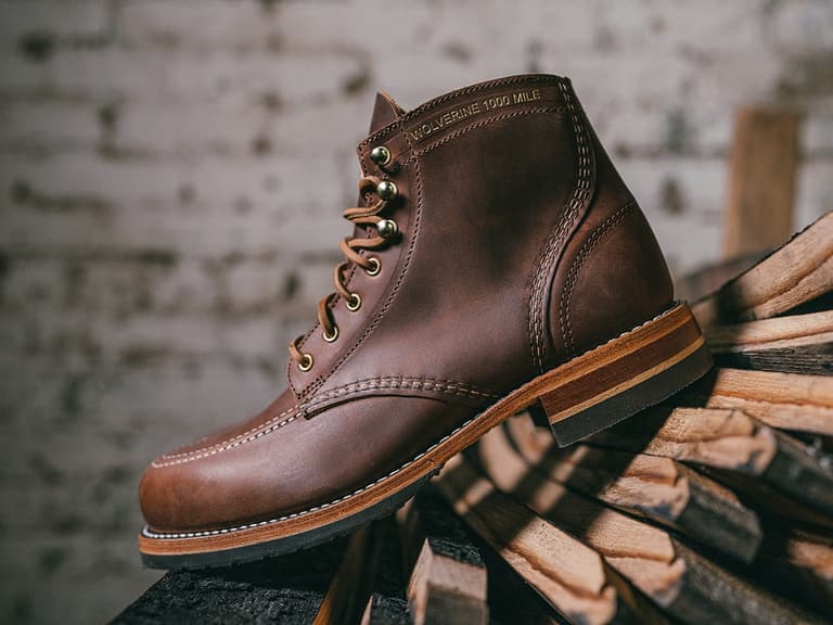Wolverine x Old Rip Van Winkle boot in brown leather with contrast stitching, displayed on stacked wood.