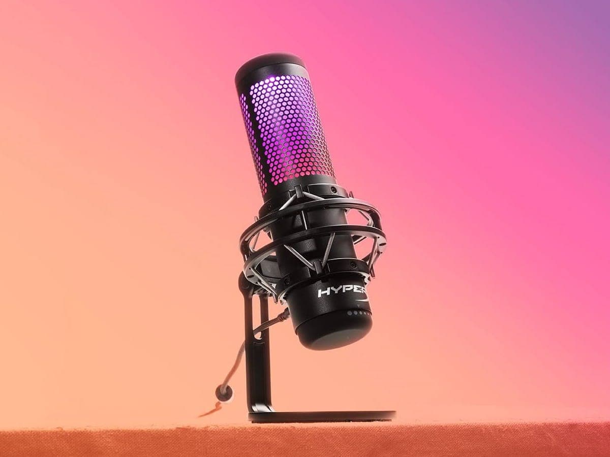 HyperX QuadCast S microphone with RGB lighting on a gradient pink and orange background.