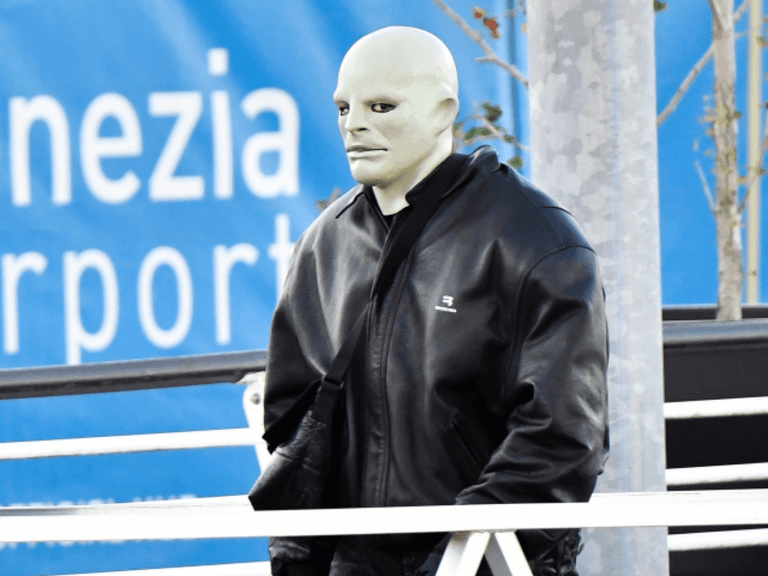 Kanye West wearing a pale face mask and black leather jacket outdoors in Italy.