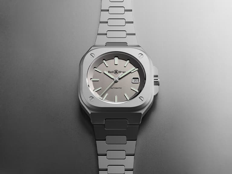 Bell & Ross BR 05 watch with grey dial and stainless steel bracelet on a grey background.