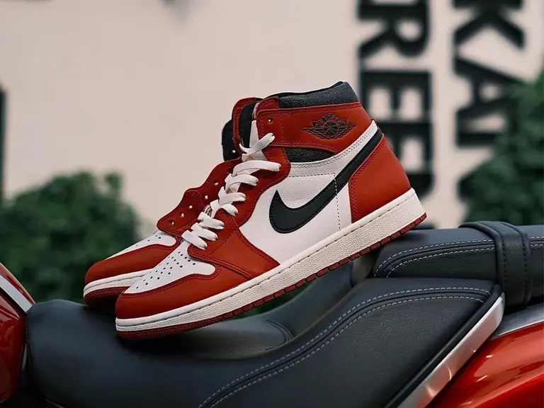 Air Jordan 1 High 'Lost and Found' sneakers in red, white, and black on a motorcycle seat.