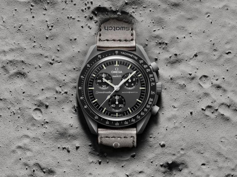 Swatch x Omega MoonSwatch watch with grey strap on lunar surface background.