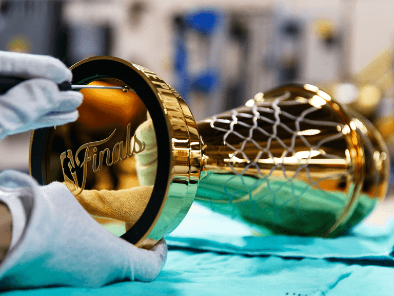 Tiffany & Co. NBA Finals Trophy being polished by a gloved hand, showcasing intricate gold detailing.