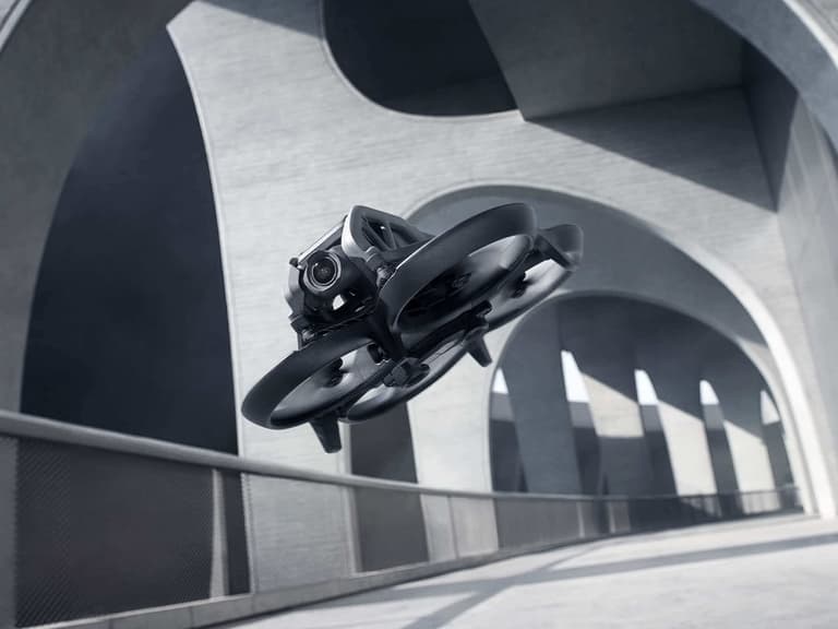 DJI Avata drone flying under modern concrete arches with a sleek black design.