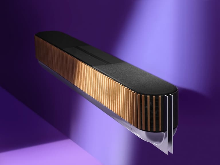 Bang & Olufsen Beosound Theatre soundbar with wood accents against a purple background.