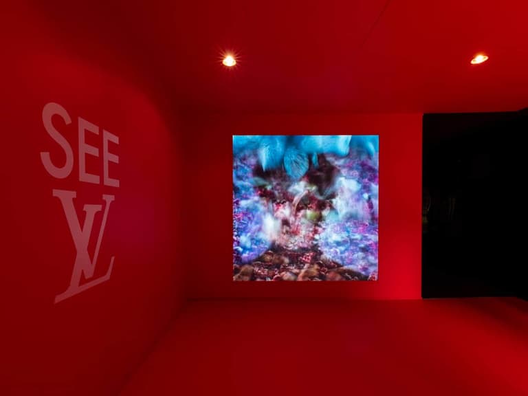 SEE LV Sydney exhibition room with vibrant red walls, featuring a large digital display of abstract blue and pink imagery.