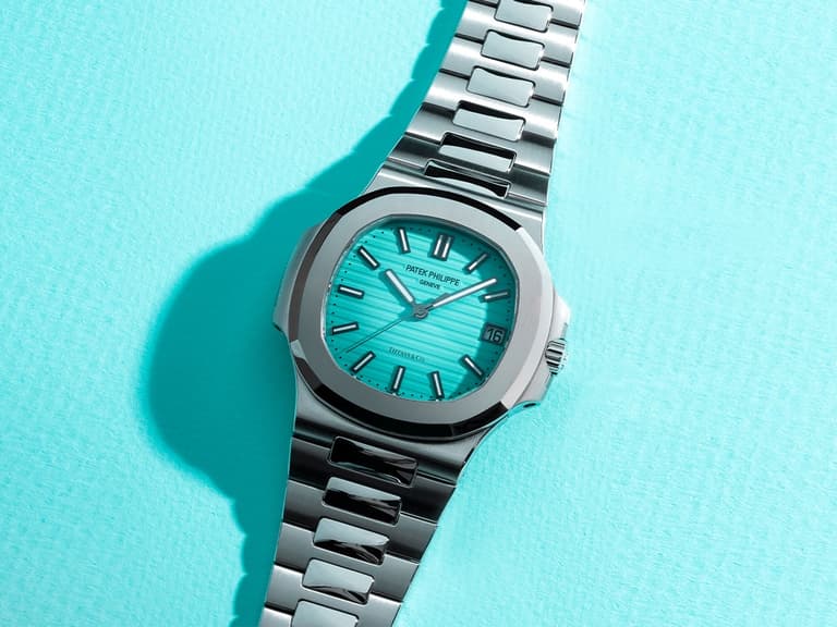Patek Philippe Nautilus watch with a Tiffany blue dial and stainless steel bracelet on a matching background.