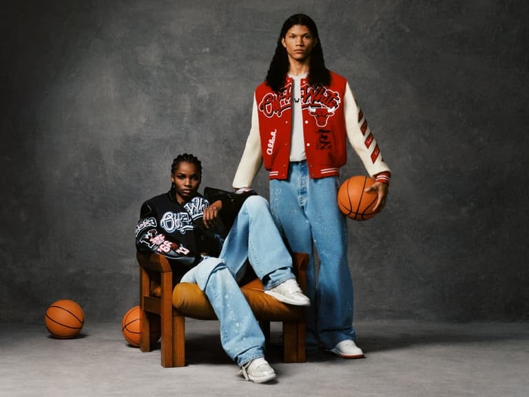 Two models wearing Off-White x Chicago Bulls varsity jackets, one seated and one standing, holding basketballs.