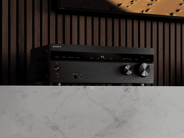 Sony STR-AN1000 8K receiver in black, positioned on a marble surface against a wooden panel backdrop.