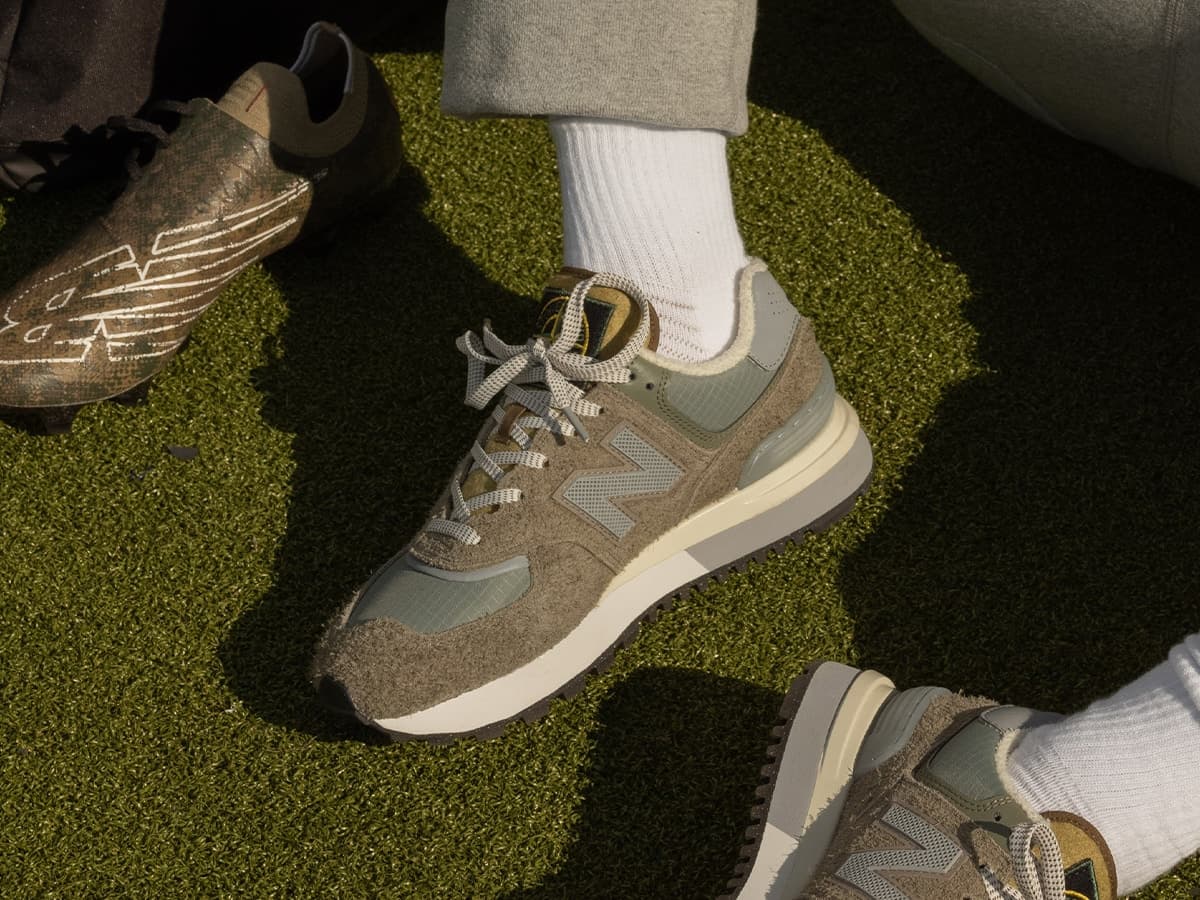 Stone Island x New Balance 574 Legacy sneakers in grey and green on grass.
