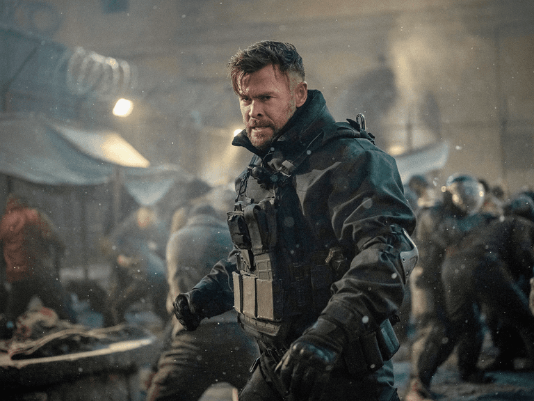 Chris Hemsworth in tactical gear amidst a chaotic fight scene in Extraction 2.