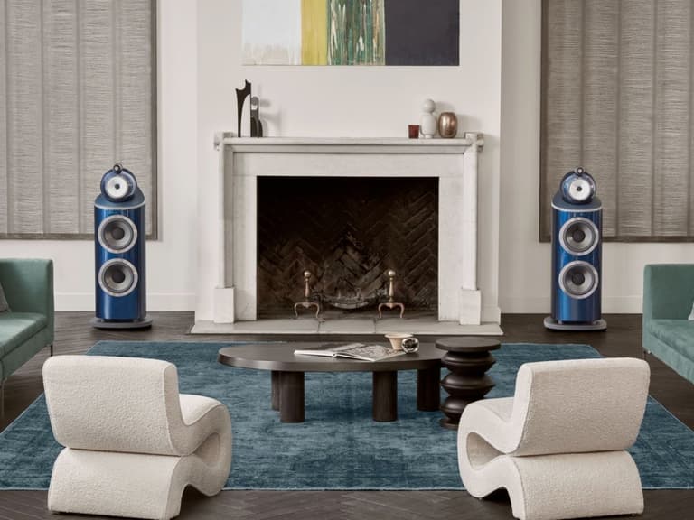 Bowers & Wilkins 800 D4 Signature speakers in blue flank a modern fireplace in an elegant living room setting.