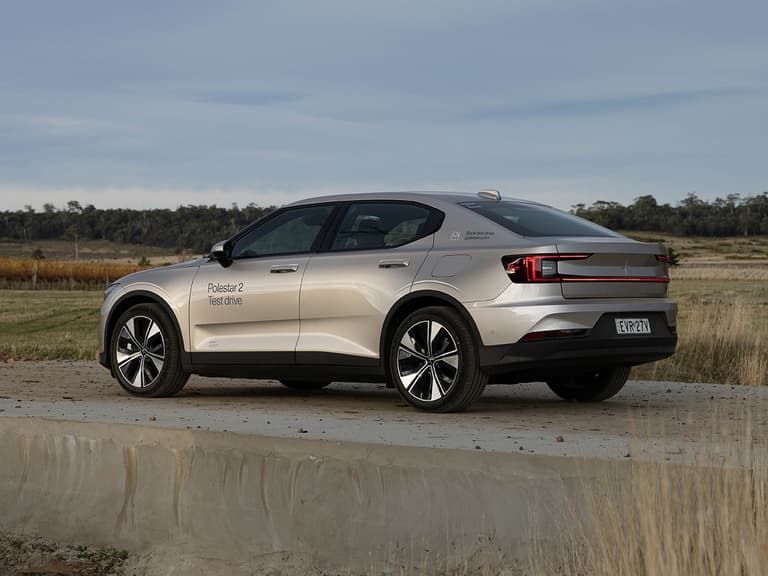 Polestar 2 in silver parked on a concrete surface with a scenic rural backdrop.