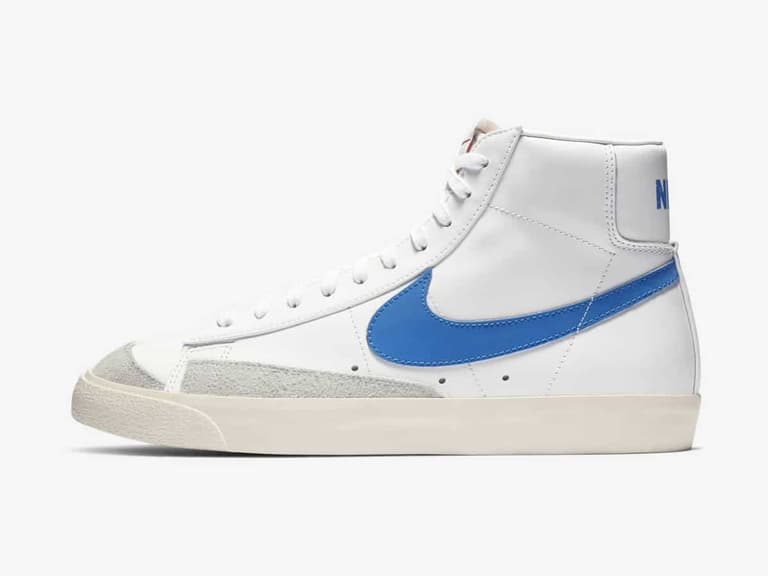 Nike Blazer Mid '77 in white with blue swoosh, side view on white background.