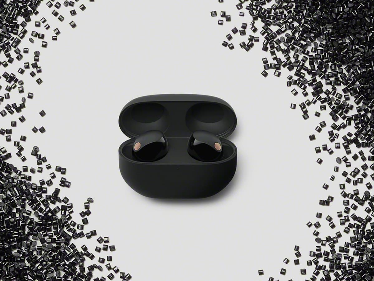 Sony WF-1000XM5 earbuds in black case surrounded by scattered black squares on a light background.