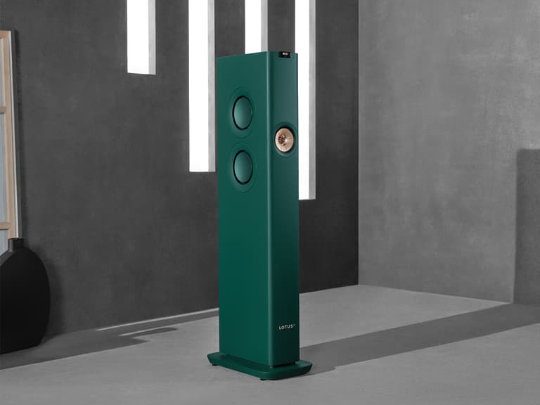 KEF LS60 Wireless Lotus Edition speaker in green, standing in a modern grey room with vertical light strips.