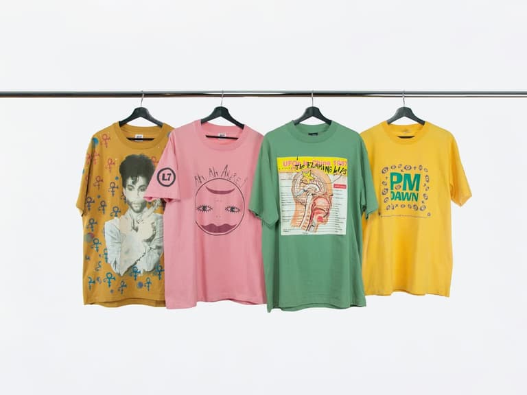 Four vintage t-shirts on hangers, featuring colourful graphic designs, displayed on a clothing rack.