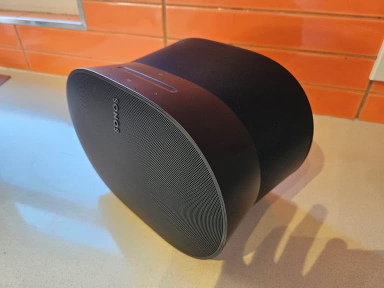 Sonos Era 300 speaker in black on a kitchen countertop with orange tiled backsplash.