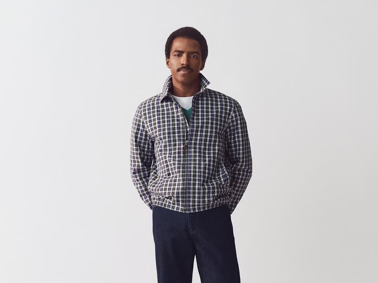 Model wearing J.Crew plaid jacket and dark jeans stands against a plain white background.
