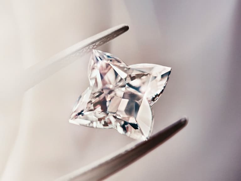 Louis Vuitton star-shaped diamond held by tweezers, showcasing its intricate facets and clarity.