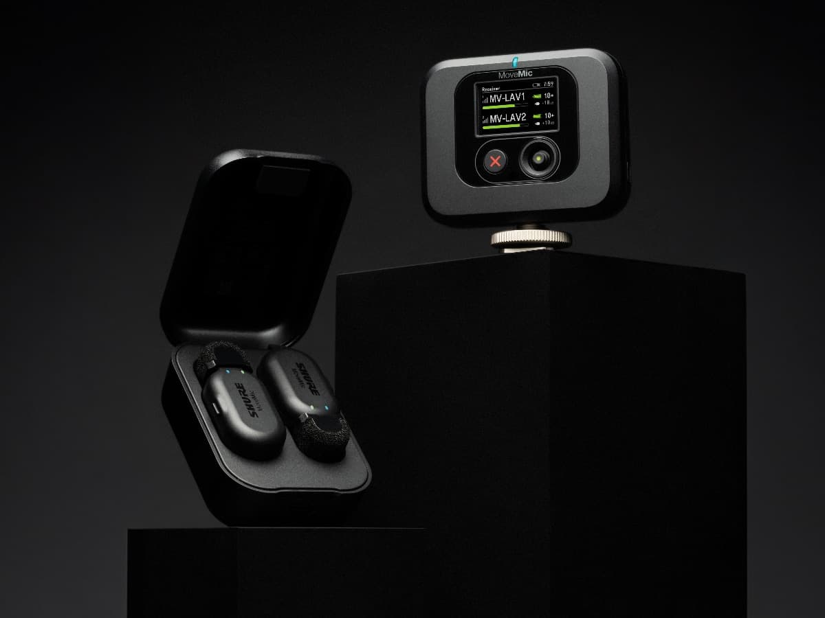 Shure MoveMic wireless lapel mic displayed with charging case on black pedestals.