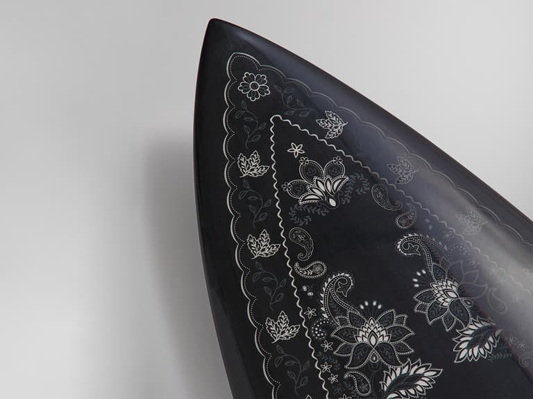 Haydenshapes surfboard features intricate white floral and paisley patterns on a sleek black background.
