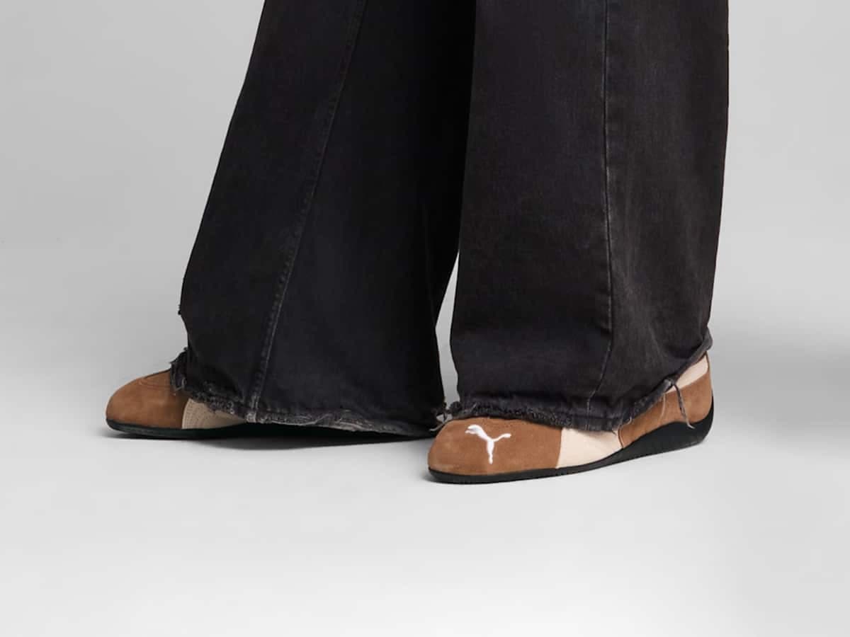 Puma Speedcat sneakers in tan and black worn with wide-leg black jeans.