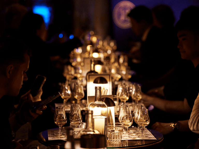Candlelit table with whisky glasses and bottles at Sydney Whisky Month event.