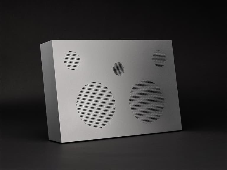 Nocs Design Monolith speaker in aluminium with perforated front panel on a dark background.