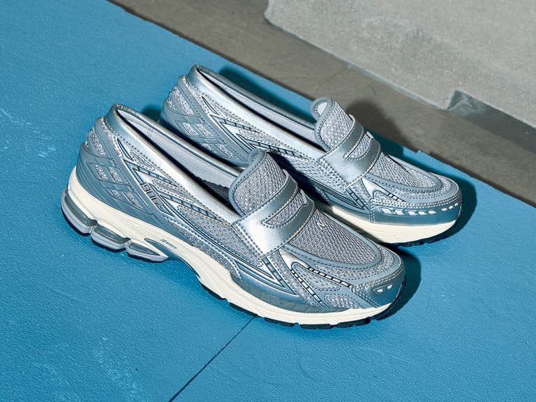 New Balance 1906L loafers in metallic silver on blue and grey background.