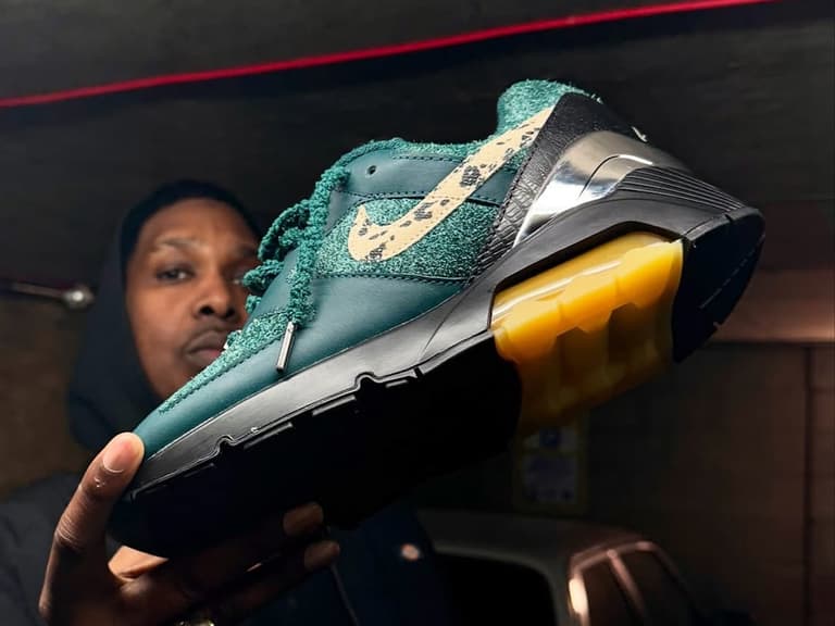 Apron Records x Air Max 180 sneaker in green with speckled swoosh and translucent sole held by person.