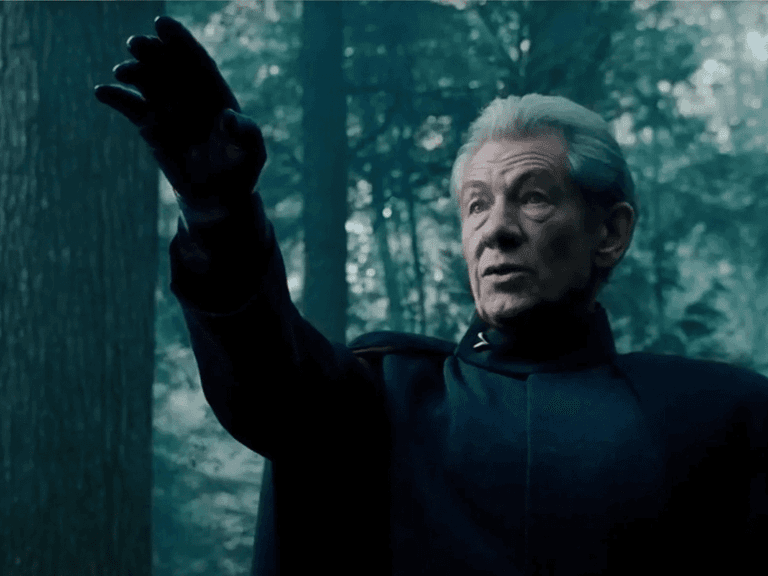 Ian McKellen as Magneto extends his arm in a forest setting, wearing a dark cape with a serious expression.