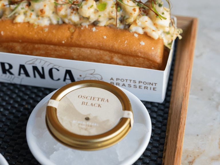 Franca's Moreton Bay bug roll with Oscietra black caviar in a tin on a white dish.