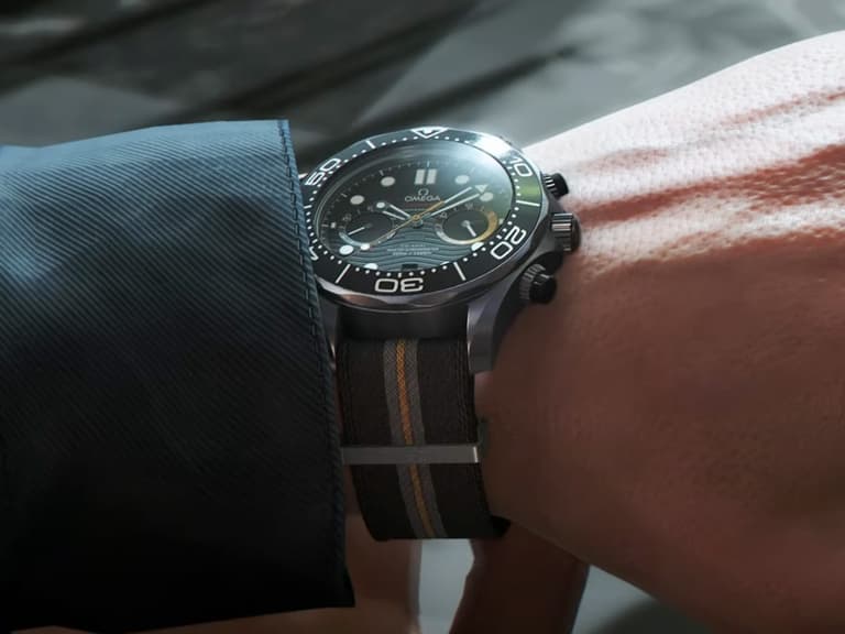Omega Seamaster Diver 300M Chronograph on wrist, black dial, striped NATO strap, close-up view.