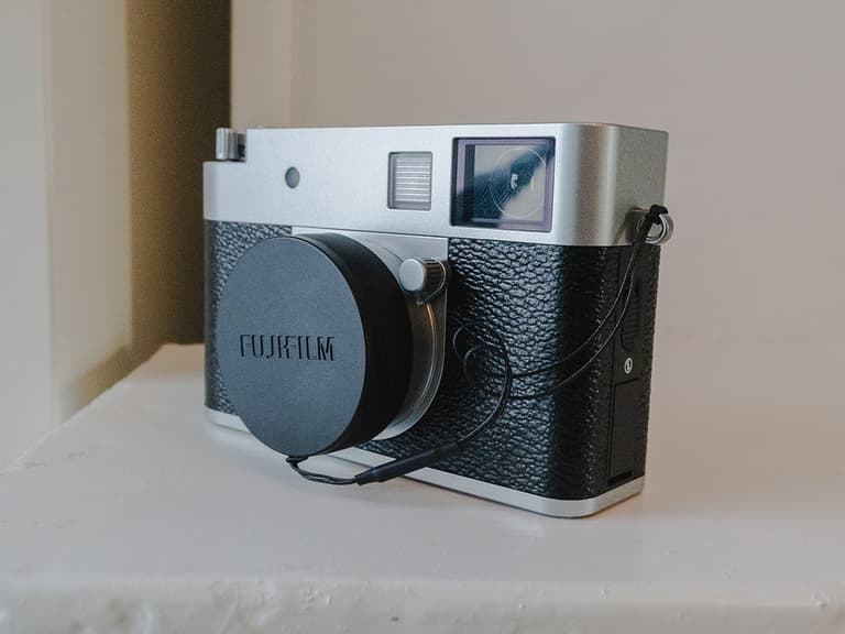 Fujifilm X-Half camera with black leather finish and silver accents on a white surface.