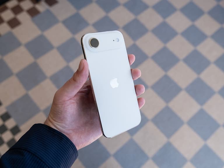 iPhone 17 Air in white held in hand, showcasing its sleek design and Apple logo against a tiled floor background.