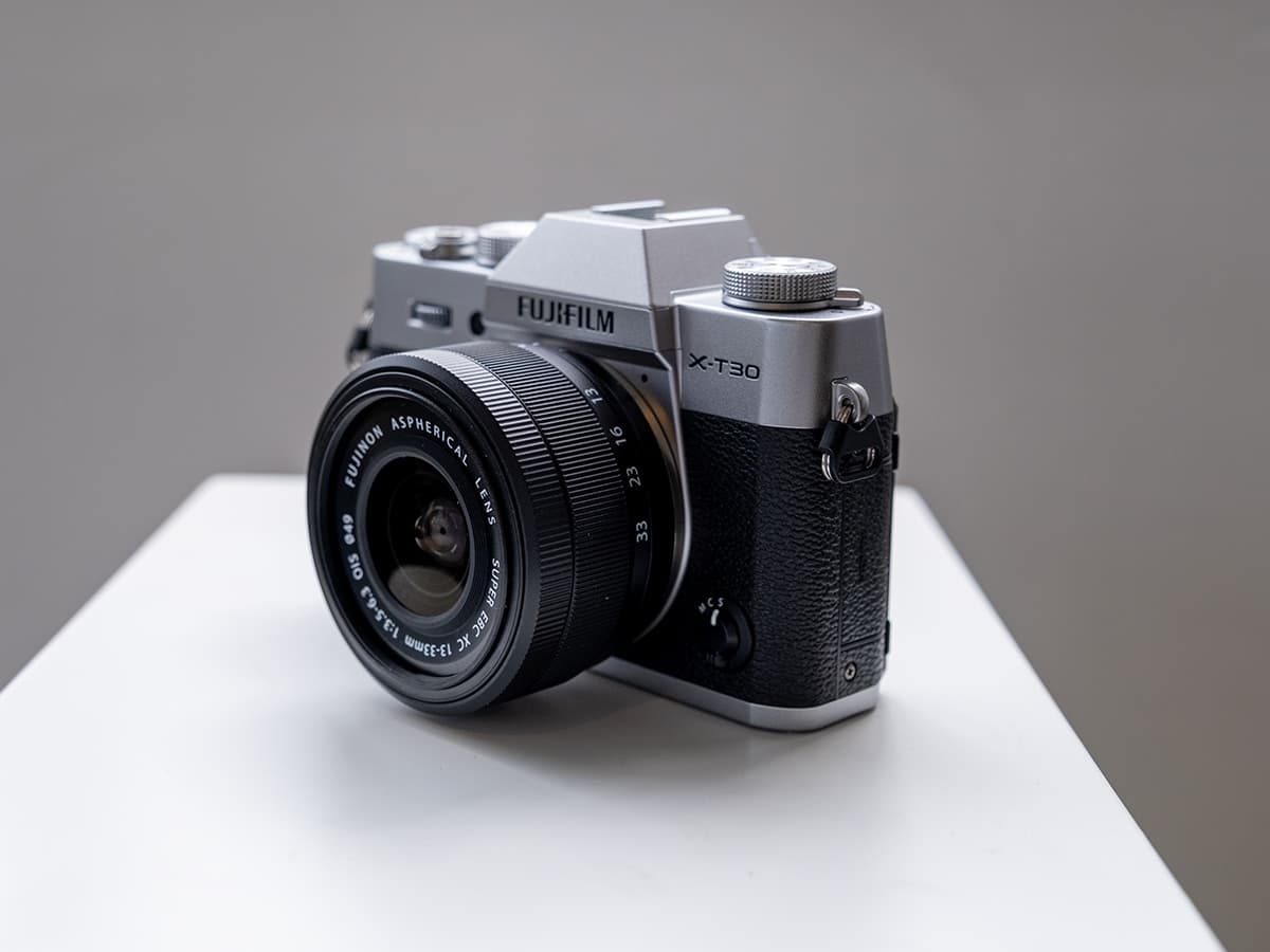 Fujifilm X-T30 III camera in silver and black on a white surface, angled view.