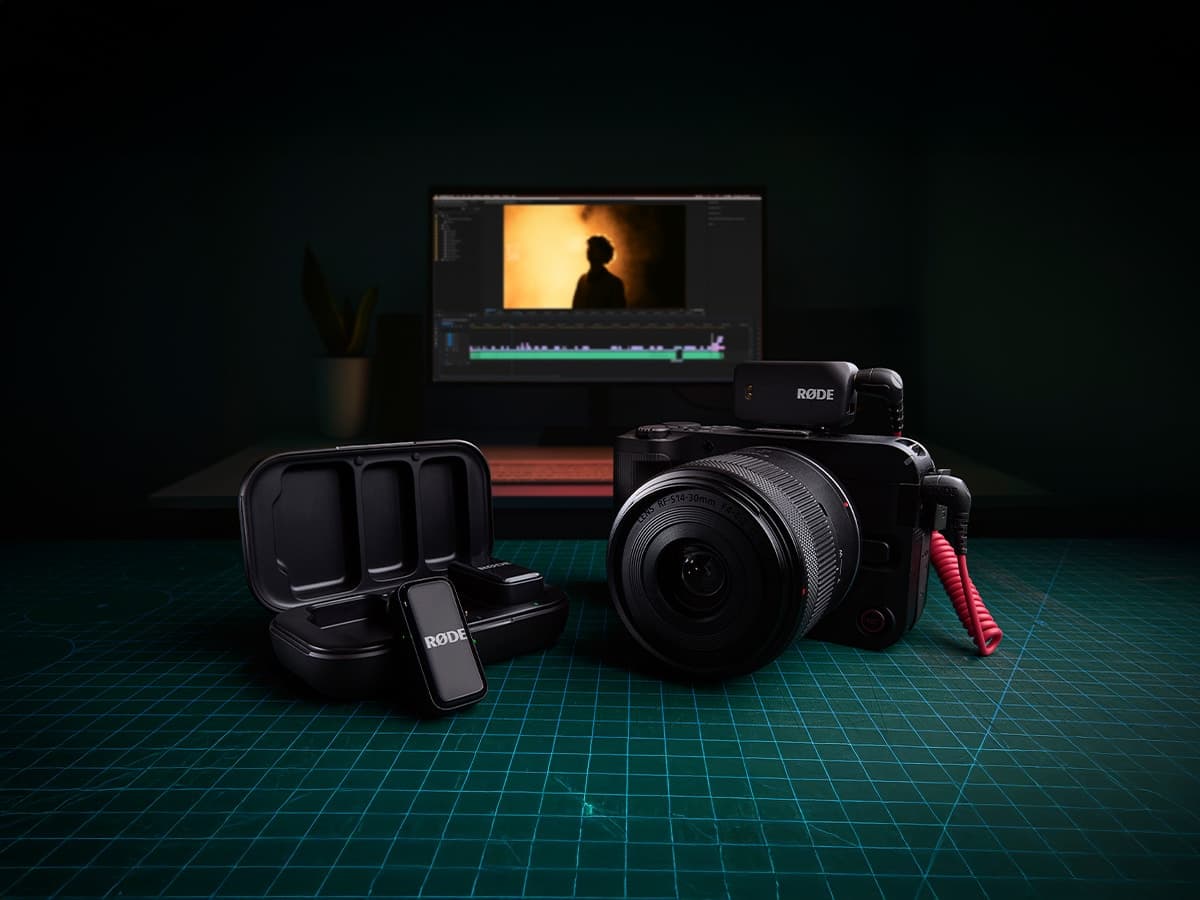 RØDE Wireless Micro Camera Kit on a green grid surface with a laptop in the background displaying video editing software.