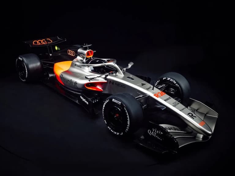 Audi R26 Formula 1 car in silver and red, showcased against a dark background.